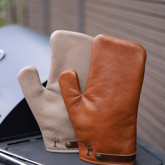 Premium Grill-Handschuh aus Leder – Whiskybraun und Smokegrau, auf einem Grill stehend